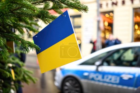 Foto de Bandera de Ucrania en un árbol de Navidad contra Alemania coche de policía y tráfico de la ciudad - Imagen libre de derechos