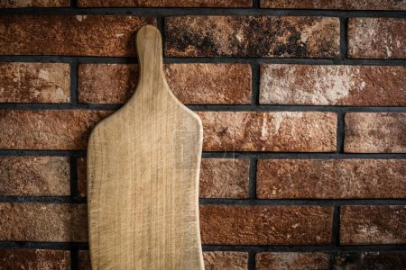 Téléchargez les photos : Wooden cutting board at the kitchen against bricks wall - en image libre de droit