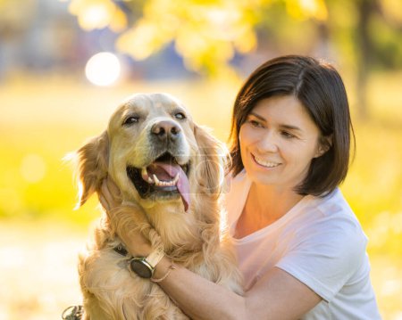 Téléchargez les photos : Fille avec beau chien récupérateur d'or, portrait sur un fond flou - en image libre de droit