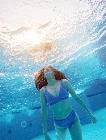 Photo for Teen girl swimming under water in blue pool. Pretty female teenager diving and enjoying summer activity - Royalty Free Image