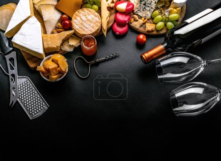 Photo for Different kinds of cheese served with wine bottle, glasses and grape for gourmet nutrition. Organic parmesan and brie set with alcohol composition - Royalty Free Image