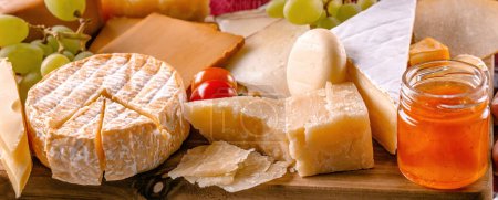 Foto de Parmesano y diferentes tipos de queso servido con uva y miel de primer plano. Colección de delicatessen de brie y camambert ecológico - Imagen libre de derechos