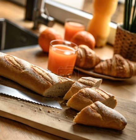Téléchargez les photos : Baguette fraîche sur une planche à découper à la cuisine. Cuisine petit déjeuner français frais. - en image libre de droit