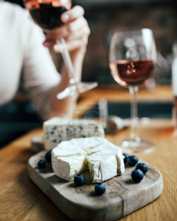 Foto de Las mujeres que beben un vino de rosas con queso brie francés plato en una mesa - Imagen libre de derechos