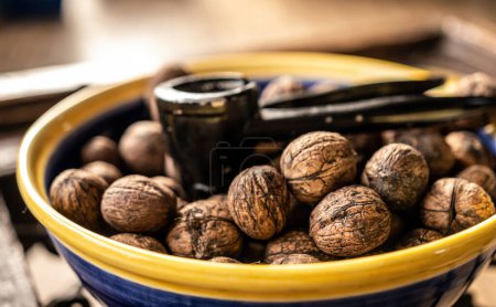 Téléchargez les photos : Walnuts and nutcracker in bowl closeup. Deicious nuts for vegetarian heathy diet and protein nutrition - en image libre de droit