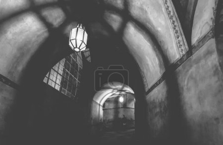 Téléchargez les photos : Lumière de la lampe et les ombres dans le couloir mystérieux dans le vieux donjon dans le château, noir et blanc - en image libre de droit