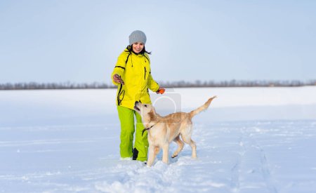 Foto de Mujer sonriente con lindo perro joven retriever en paseo de invierno - Imagen libre de derechos