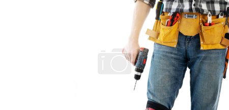 Téléchargez les photos : Homme portant une ceinture de montage avec des outils pour la réparation tenant la perceuse dans les mains isolées sur fond blanc. Équipement professionnel de bricoleur - en image libre de droit