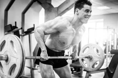 Photo for Musculed bodybuilder doing barbell bent-over rows - Royalty Free Image