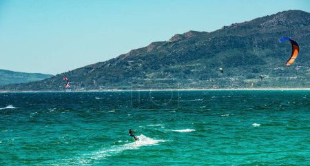 Téléchargez les photos : Kite surf sport dans les vagues de l'océan à l'été dans des paysages pittoresques. Kiteboard actif dans l'eau de mer avec adrénaline - en image libre de droit