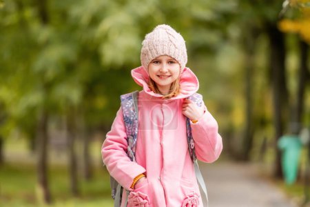 Photo for School girl with backpack looking at camera at autumn park. Preteen child portrait oudoors - Royalty Free Image