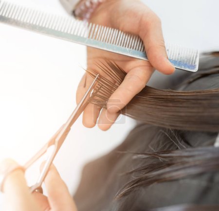 Photo for Hairdresser hands with scissors make hair cut in a beauty salon. Close up view - Royalty Free Image
