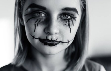 Foto de Niña con espeluznante maquillaje de Halloween ojos cepillados mirando a la cámara. Retrato de niños espeluznantes con expresión de bromista loco, blanco y negro. - Imagen libre de derechos