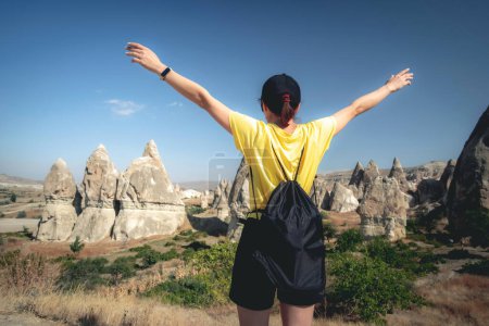 Téléchargez les photos : Femme touriste debout en arrière avec les mains levées sur fond de montagnes turques en Cappadoce - en image libre de droit