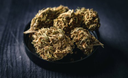 Photo for Dry CBD cannabis, also known as dried hemp flowers on a wooden table - Royalty Free Image