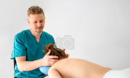 Foto de El masajista que hace el masaje por el cuello de las muchachas en el salón de masaje. Procedimientos sanitarios y de relajación. - Imagen libre de derechos