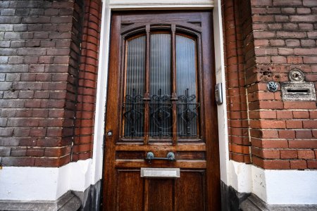 Photo for Wooden door with glass in european residential brick building. House entrance and stone traditional facade - Royalty Free Image