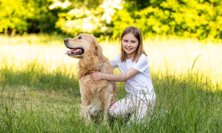 Téléchargez les photos : Mignon fille étreinte avec adorable golden retriever chien à l'extérieur - en image libre de droit