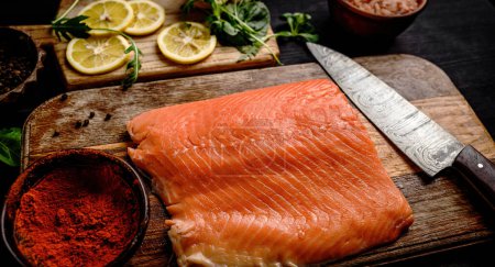 Téléchargez les photos : Filet de saumon cru avec couteau, épices et citrons sur table en bois. Poisson oméga rouge sain et basilic vert à la cuisine - en image libre de droit
