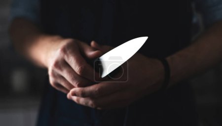 Foto de ManS manos agarre cuchillo de cocina como jefe se prepara para cocinar con cuchillo afilado contra fondo negro - Imagen libre de derechos