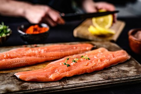 Téléchargez les photos : Cuisson filet de truite de poisson rouge frais sur une planche à découper sur la table de cuisine - en image libre de droit