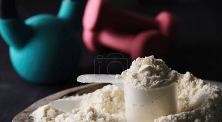 Photo for Measuring spoon with dry sports protein with sport equipment on a table - Royalty Free Image