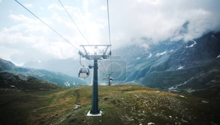Téléchargez les photos : Chemin de téléphérique dans les hautes montagnes rocheuses avec une vue spectaculaire sur la vallée - en image libre de droit