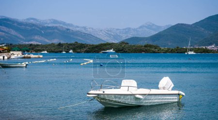 Téléchargez les photos : White boat in Adriatic sea, Montenegro with mountains and forest on background. Vessel transportation in beautiful Mediterranean nature in sunny day - en image libre de droit