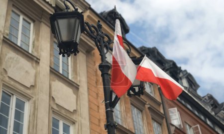 Téléchargez les photos : Drapeaux polonais dans le bâtiment de la vieille ville extérieur comme symbole du patriotisme et de l'identité nationale. Drapeau rouge et blanc flottant dans le ciel du pays européen - en image libre de droit