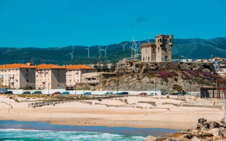 Foto de Antiguo Castillo de Guzmán El Bueno y Costa de Tarifa en Cádiz con modernos edificios y generadores de energía eólica, vista desde la playa - Imagen libre de derechos