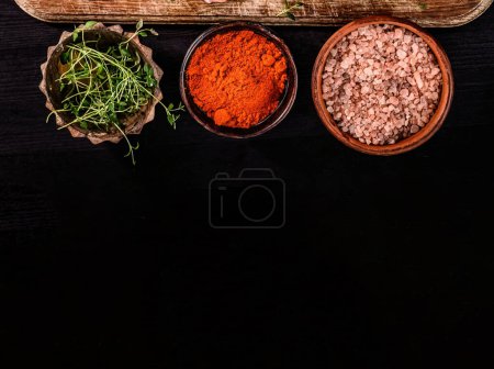 Téléchargez les photos : Aide les épices et le sel dans les bols sur une table noire, vue du dessus avec espace de copie - en image libre de droit