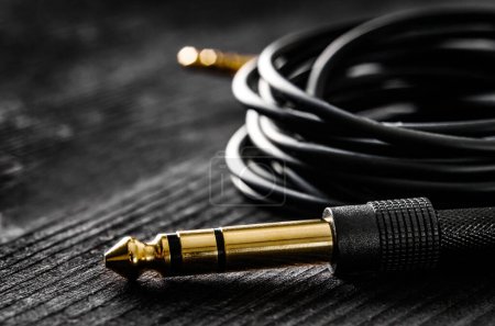 Photo for Audio cable with Jack and mini jack connectors, on a dark table, close up view - Royalty Free Image