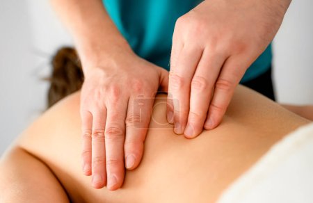 Foto de Masajista profesional haciendo masaje de puntos gatillo en la espalda en la sala de masajes - Imagen libre de derechos