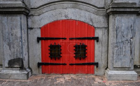 Téléchargez les photos : Porte rouge traditionnelle avec design en pierre de construction mur de château. Entrée de la maison à l'ancienne dans la ville européenne - en image libre de droit