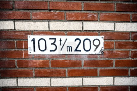 Téléchargez les photos : Panneau d'adresse sur le mur de briques du bâtiment résidentiel avec des numéros. Panneau d'identification de maison sur façade en pierre - en image libre de droit