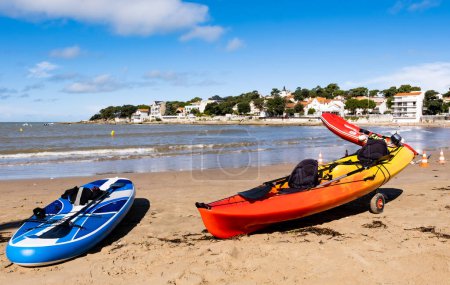Téléchargez les photos : Kayaks sur la belle plage de la mer par temps ensoleillé avec des maisons méditerranéennes en arrière-plan. Pêche et transport sur le paysage marin pittoresque - en image libre de droit