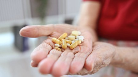 Foto de Las manos de la anciana sostienen píldoras y cápsulas en vista de cerca - Imagen libre de derechos