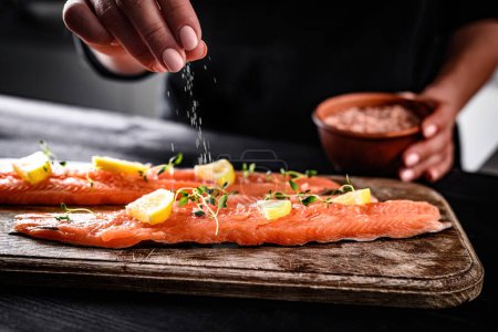 Téléchargez les photos : Chef Salage cru truite rouge poisson pour la cuisson avec du citron à la cuisine - en image libre de droit