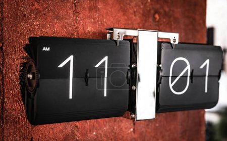 Foto de Voltear el reloj negro con once horas en el primer plano del panel. Reloj con números de horas y minutos - Imagen libre de derechos