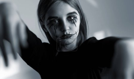 Foto de Niña con maquillaje de Halloween espeluznante mirando a la cámara como zombie. Retrato infantil espeluznante en blanco y negro. - Imagen libre de derechos