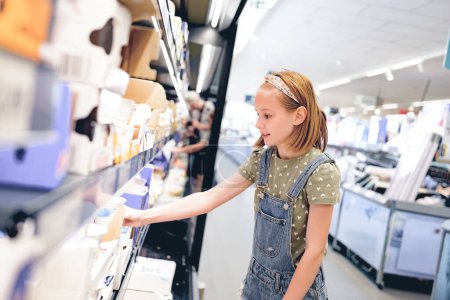Foto de Niña bonita eligiendo yogur en el supermercado. Hermosa niña preadolescente femenina que busca productos lácteos en la tienda de comestibles - Imagen libre de derechos