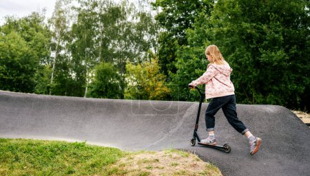 Foto de Chica preadolescente montando scooter en rampa en el parque. Lindo niño con vehículo ecológico al aire libre - Imagen libre de derechos