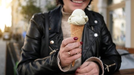 Foto de Elegante hembra disfruta sosteniendo sabroso helado en gofres mientras explora las calles de la ciudad - Imagen libre de derechos