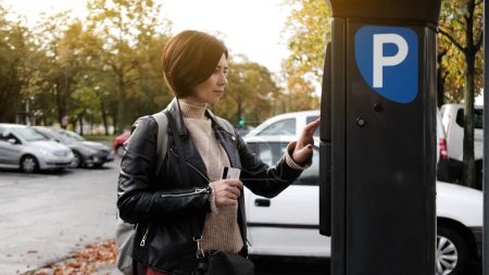 Téléchargez les photos : Femme paie pour le stationnement de voiture via un compteur de stationnement à l'aide de la carte de crédit - en image libre de droit