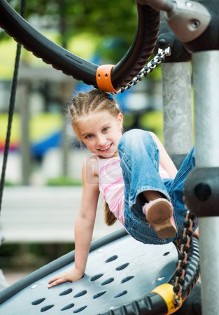 Téléchargez les photos : Bonne petite fille jouant à l'aire de jeux en plein air - en image libre de droit