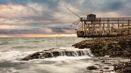 Photo for Traditional fisherman hut on stilts with carrelet fishing net. Typical wooden houses for fishing at beach - Royalty Free Image