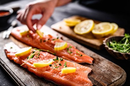 Photo for Girl cooking fillet trout red fish with lemon and herbs in the kitchen - Royalty Free Image