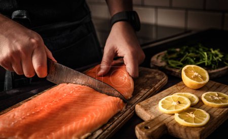 Foto de Jefe de corte de salmón pescado rojo en la cocina, cocinar una cena saludable - Imagen libre de derechos