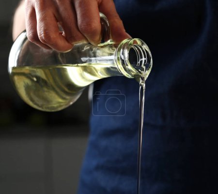 Photo for Girl Pouring Oil While Cooking Food, Vegetable Oil Is Poured From A Jug - Royalty Free Image