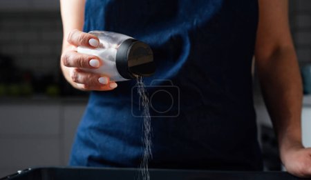 Photo for Woman Salting Food With A Salt Shaker At The Kitchen - Royalty Free Image